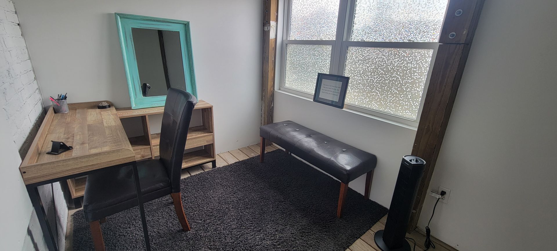 Small room office nook with desk, mirror, chair, bench, and large window.