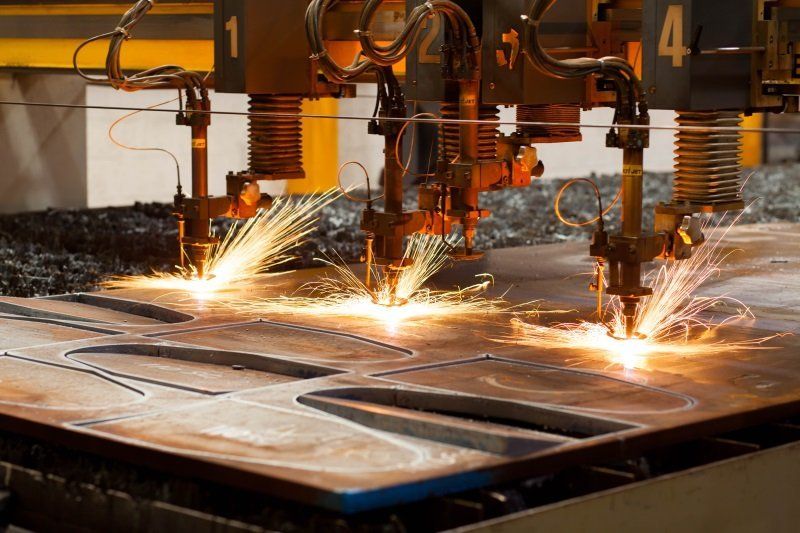 Industrial cutting machines sparking as they slice metal sheets on a factory floor