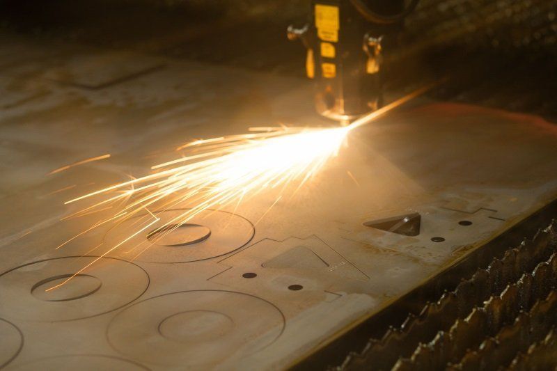 Metal cutting in progress with bright sparks over a marked sheet steel surface