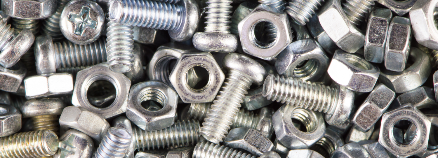 Close-up of shiny metal nuts and threaded bolts piled together