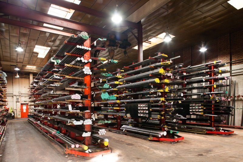Rows of skis and snowboards stored on metal racks in a warehouse-like room