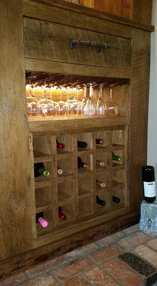 A wooden wine rack with wine bottles and glasses in it.