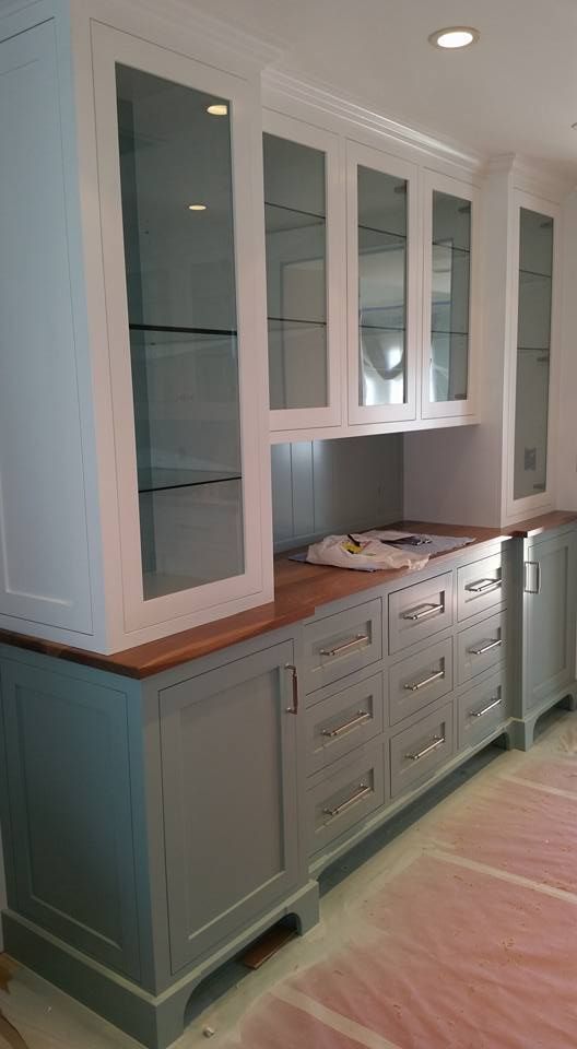 A kitchen with a lot of cabinets and drawers and glass doors.
