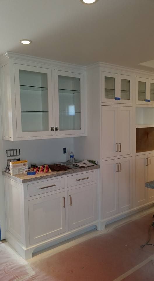 A kitchen with white cabinets and glass doors is being remodeled.