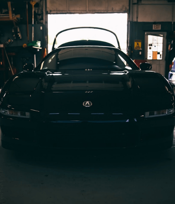 Black Acura NSX parked inside an automotive repair shop.