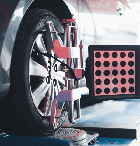Wheel alignment equipment attached to a vehicle tire in an automotive repair shop.
