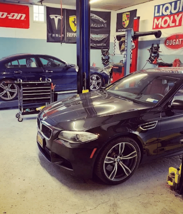 Black BMW performance sedan parked inside an automotive repair shop.