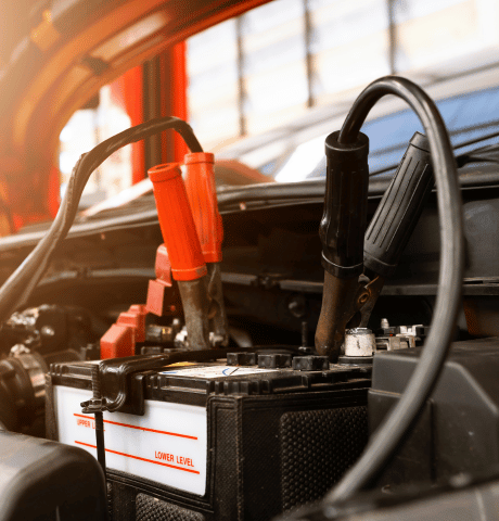 Jumper cables connected to a car battery under the hood.