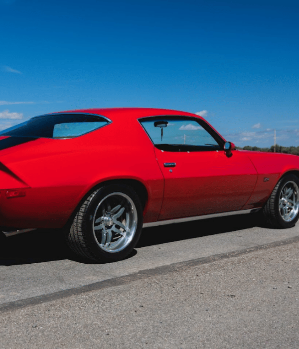 Red classic Chevrolet Camaro parked outdoors on a sunny day.