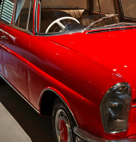 Close-up of a restored red classic car with chrome trim and vintage styling.