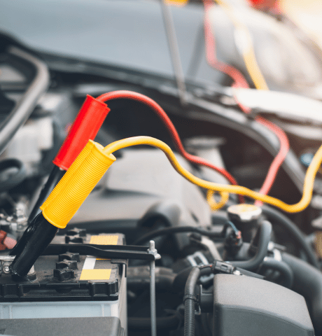 Electrical test leads connected to a vehicle battery under the hood.