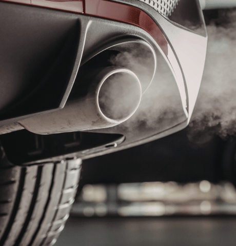 Close-up of dual vehicle exhaust pipes emitting visible exhaust fumes.