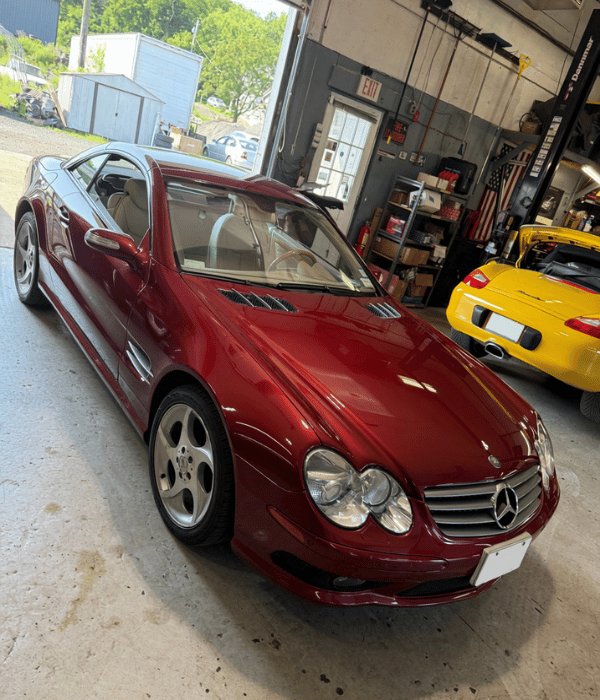 Red Mercedes-Benz sports car parked inside an automotive repair shop.