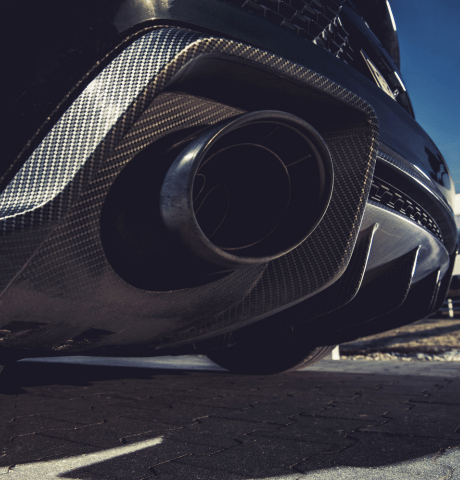Close-up of a performance exhaust tip with carbon fiber trim.