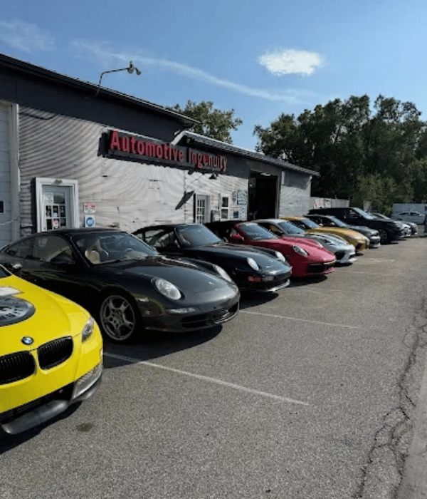 Row of Porsche sports cars and other performance vehicles parked outside Automotive Ingenuity.