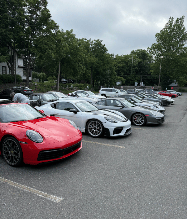 Large lineup of Porsche sports cars parked together in an outdoor lot.
