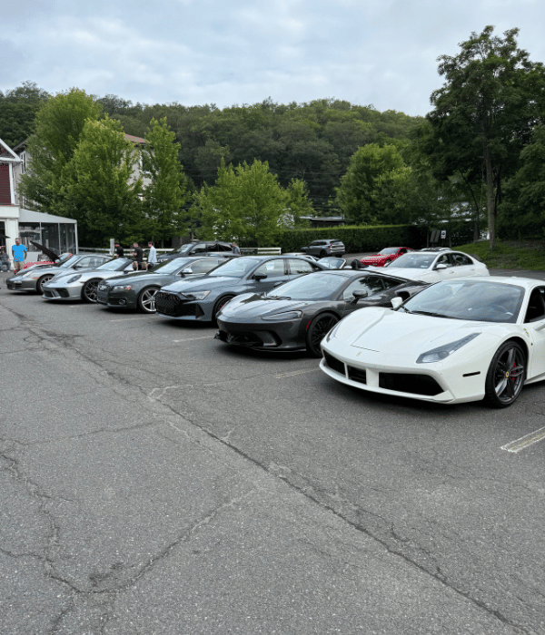 Lineup of luxury and exotic sports cars including a white Ferrari parked outdoors.