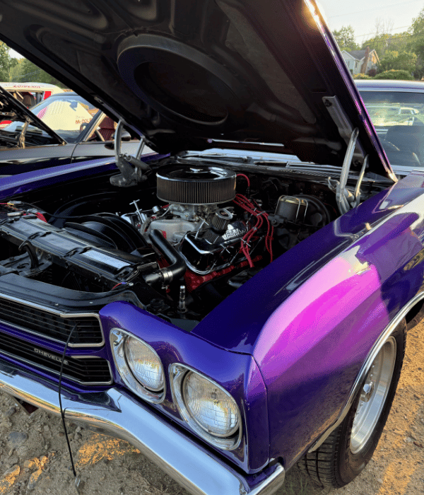Purple classic Chevrolet with its hood open displaying a performance engine.