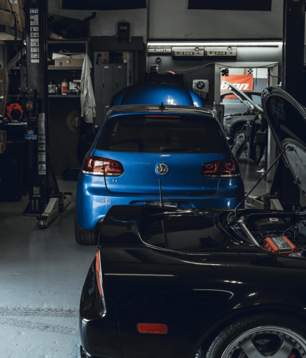 Blue Volkswagen hatchback parked inside an automotive repair shop.