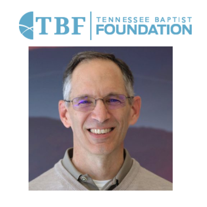 A man is smiling in front of a tennessee baptist foundation logo