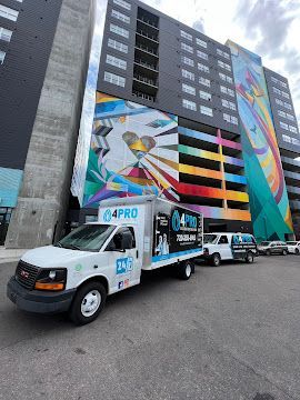Moving trucks parked beside a tall apartment building with colorful mural art