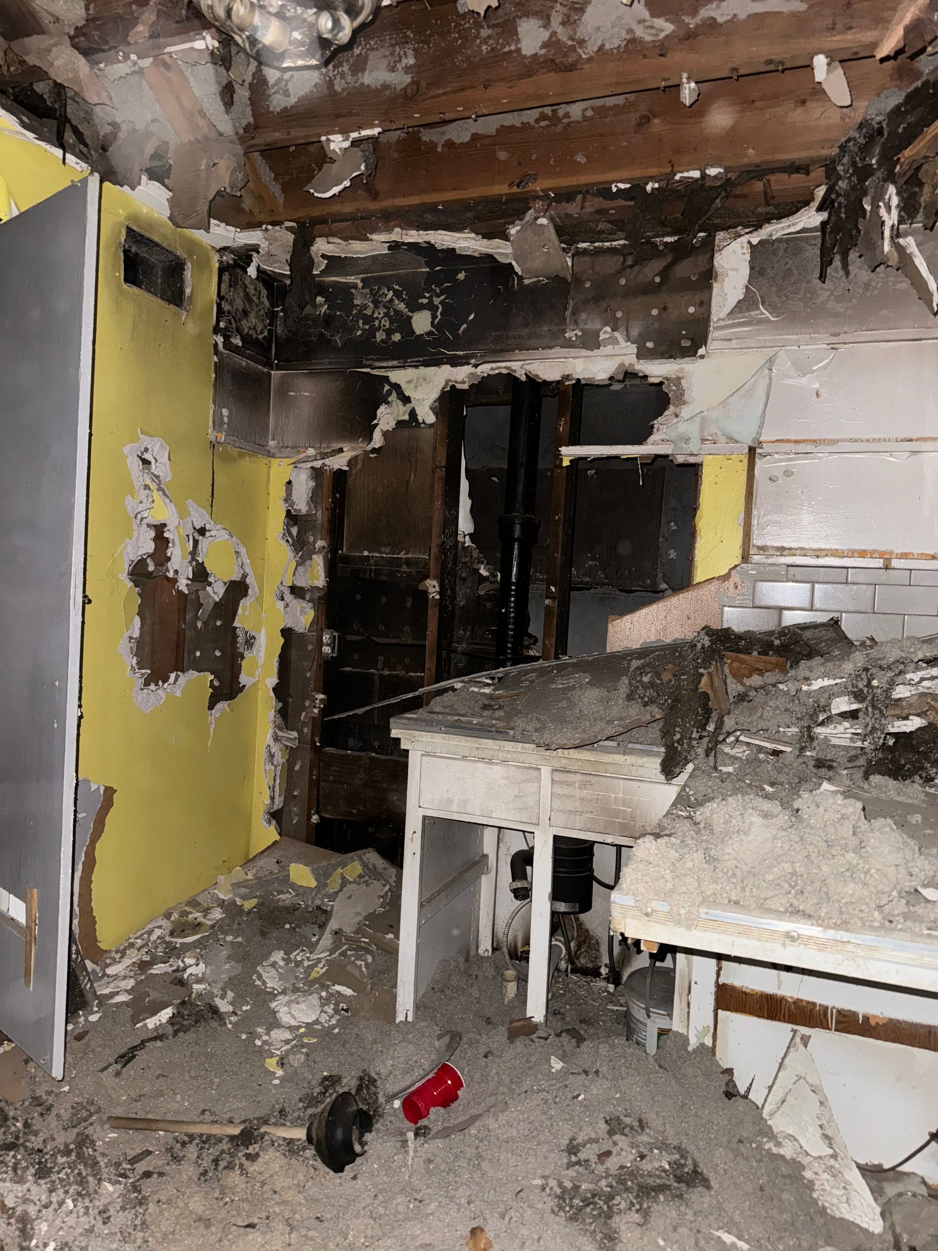 Charred, damaged room with burned walls, debris, and a table in the foreground