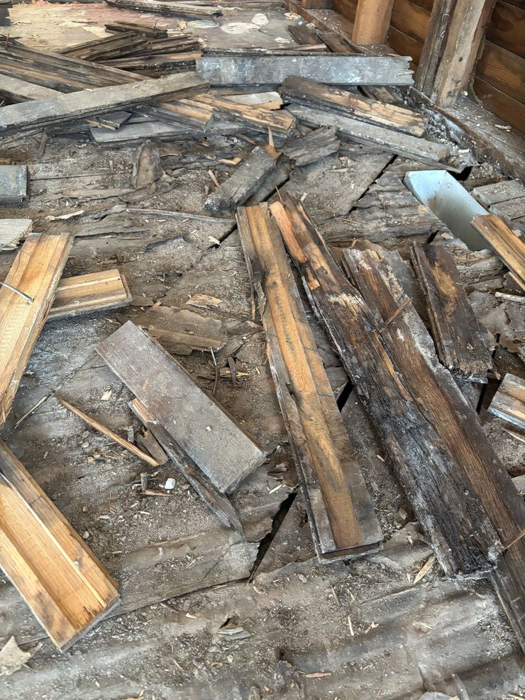 Pile of broken wooden planks and debris scattered on a rough floor.