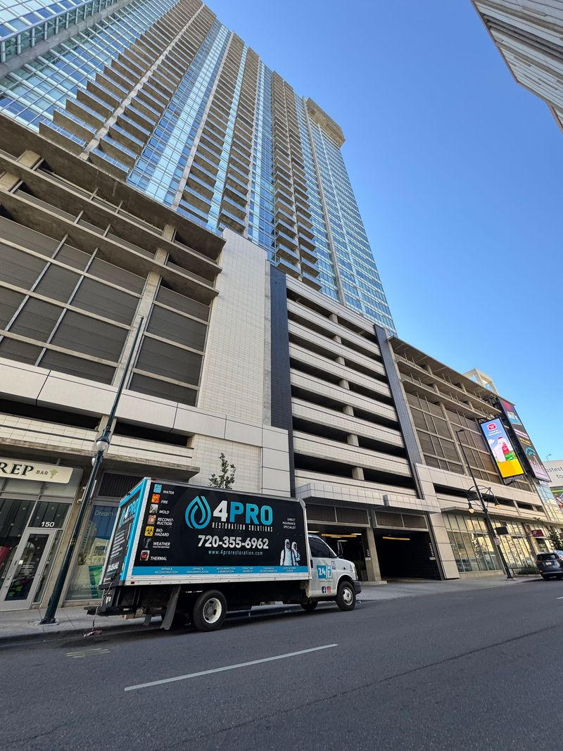 Tall city building with a 4PRO service truck parked on the street under a blue sky.