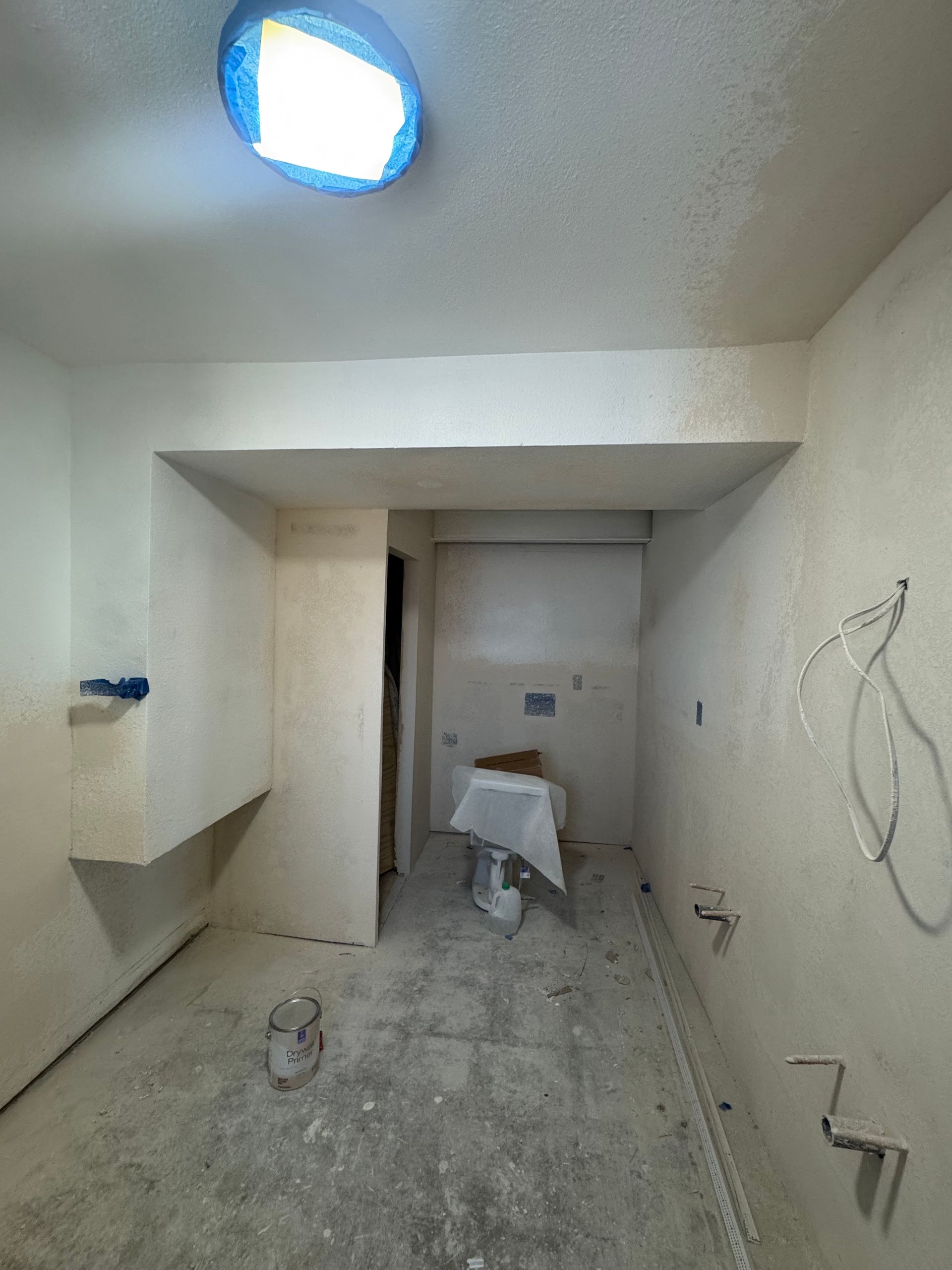 Small unfinished room under renovation with bare walls, concrete floor, and a ladder by the back opening.