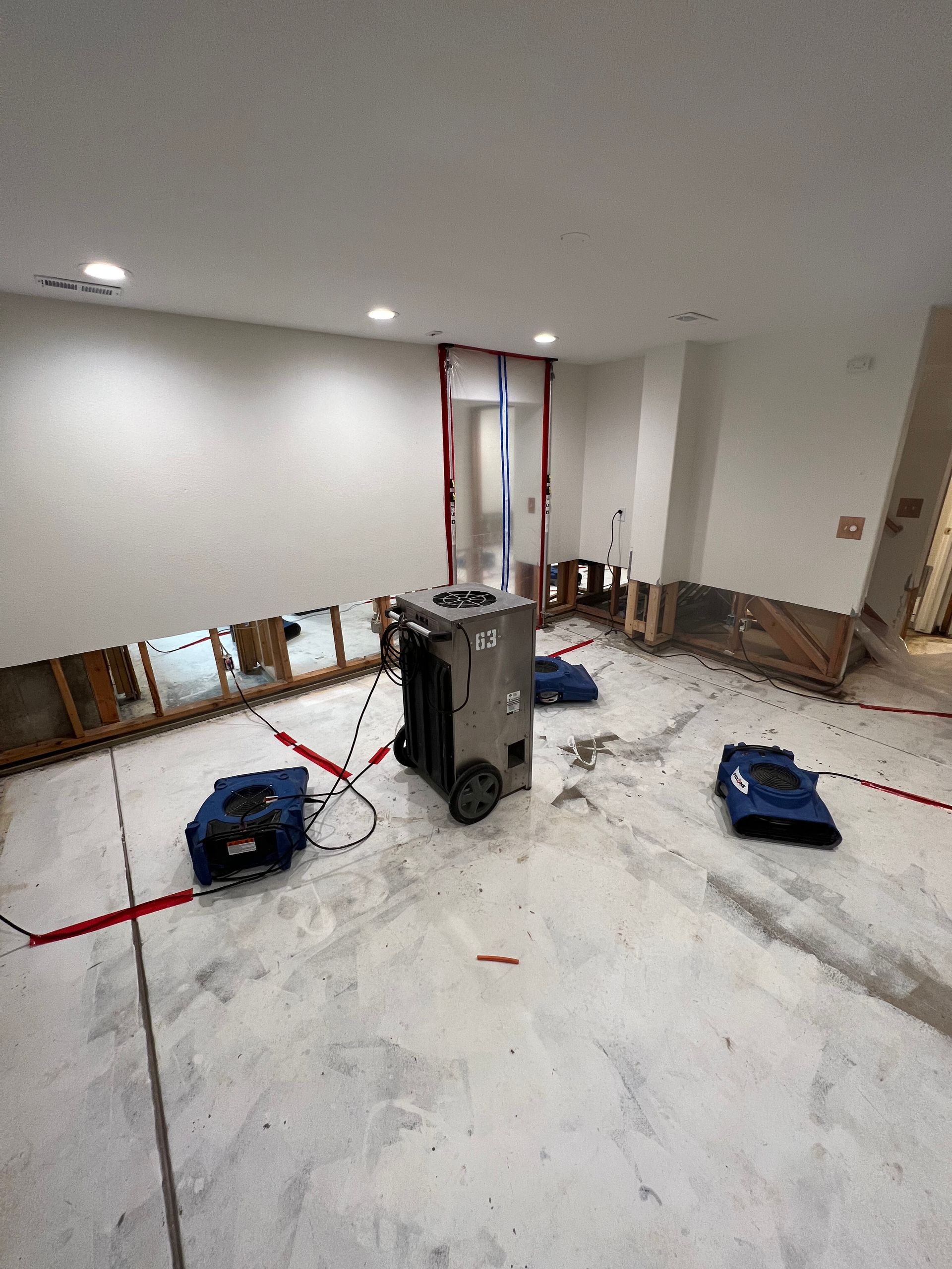 Room under renovation with tools, debris, and drywall along the walls