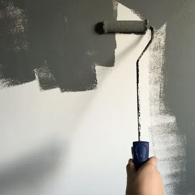 Hand painting a white wall gray with a small paint roller