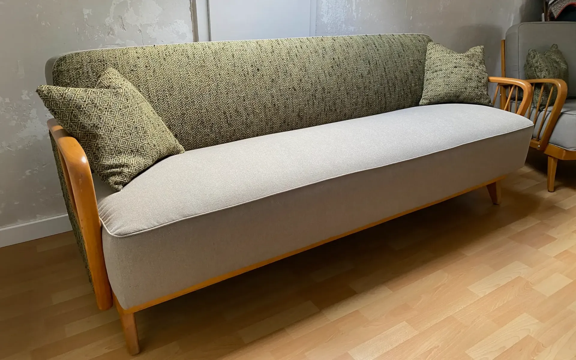 Ein dreisitziges Sofa im Mid-Century-Modern-Stil mit hellbeiger Sitzfläche, strukturierter olivgrüner Rückenlehne 