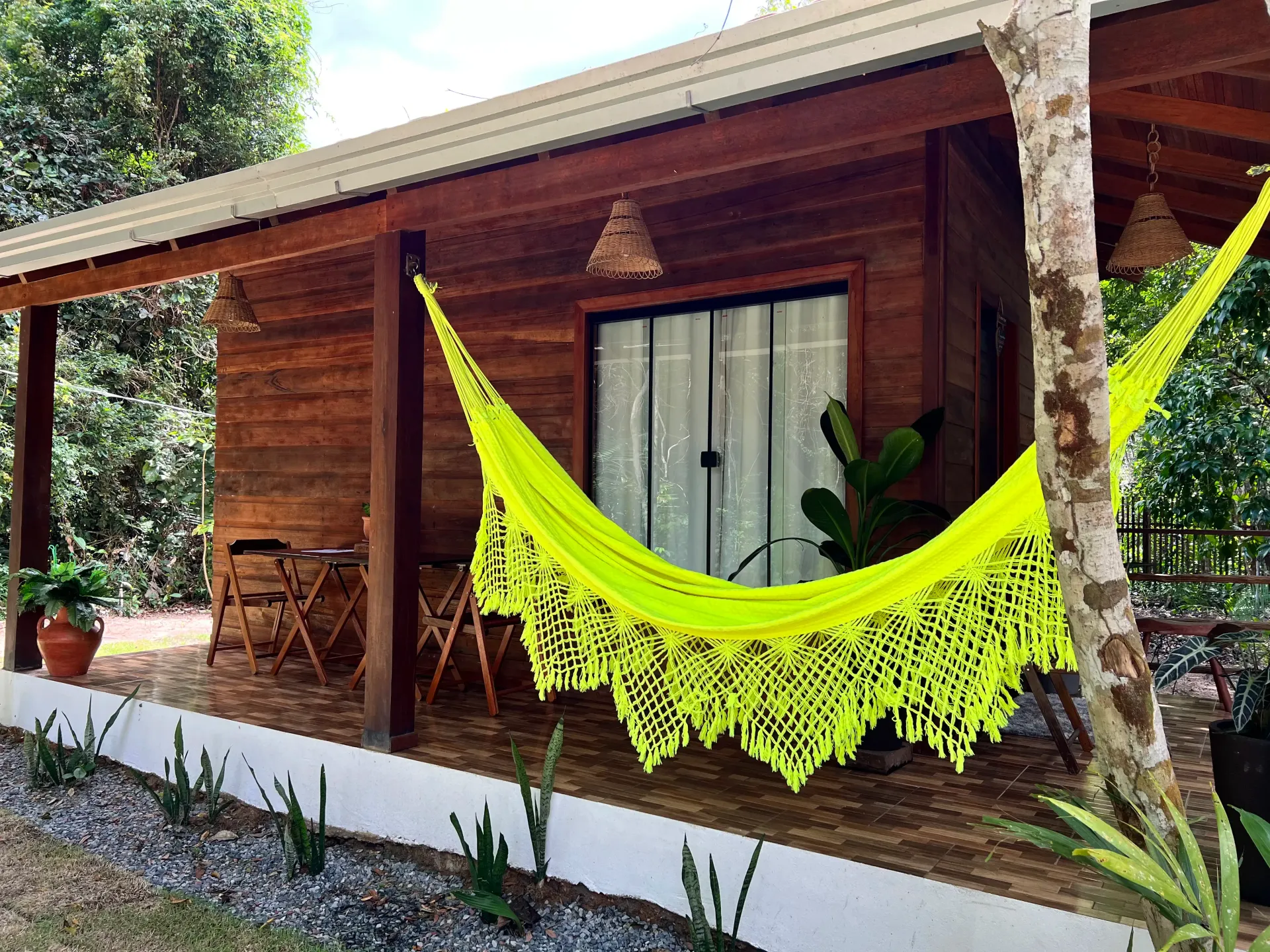 Uma casa de madeira com uma rede amarela na varanda. Pousada-Sumaúma