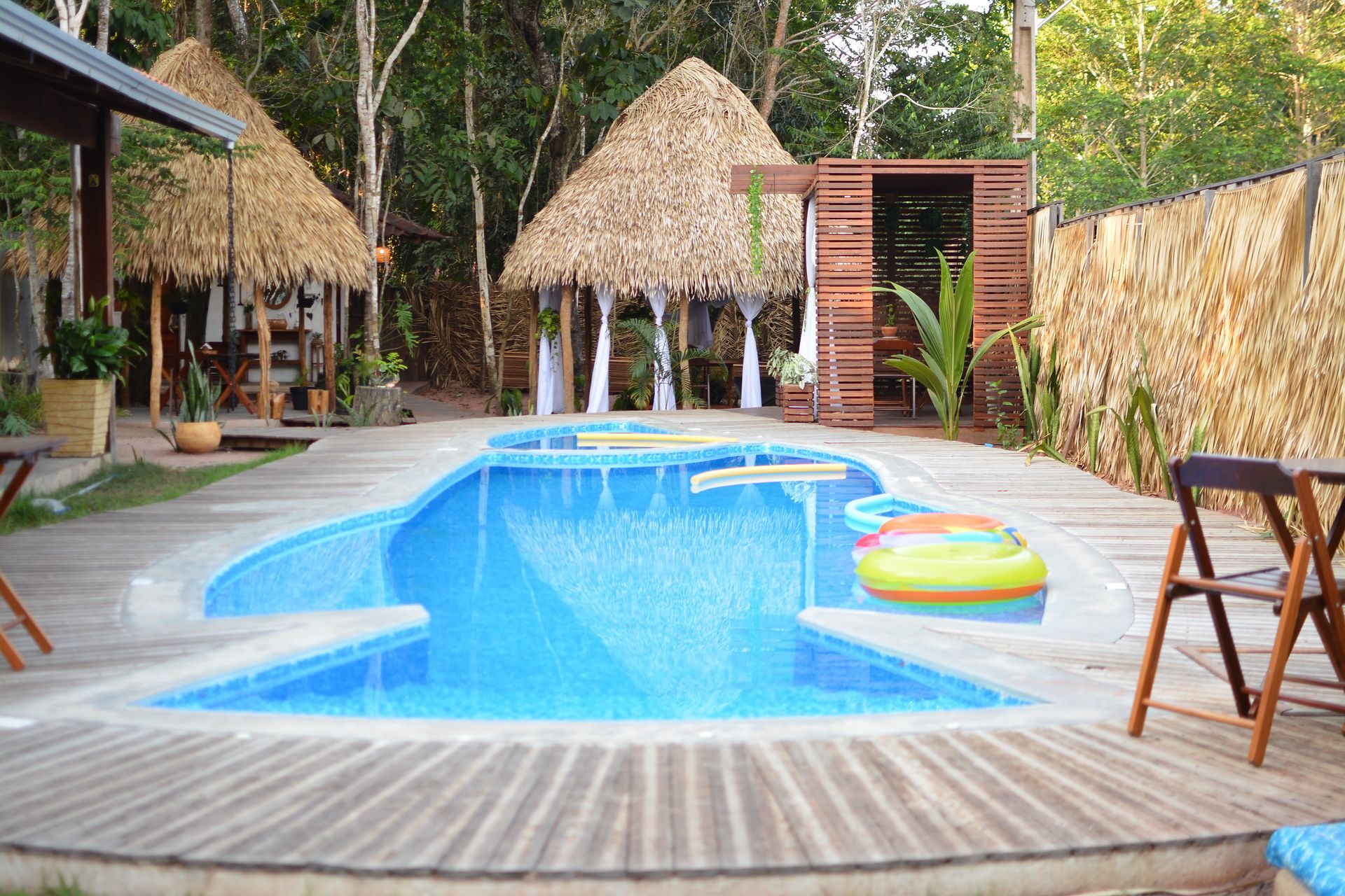 Uma grande piscina com uma cabana de palha ao fundo.  Pousada-Sumauma