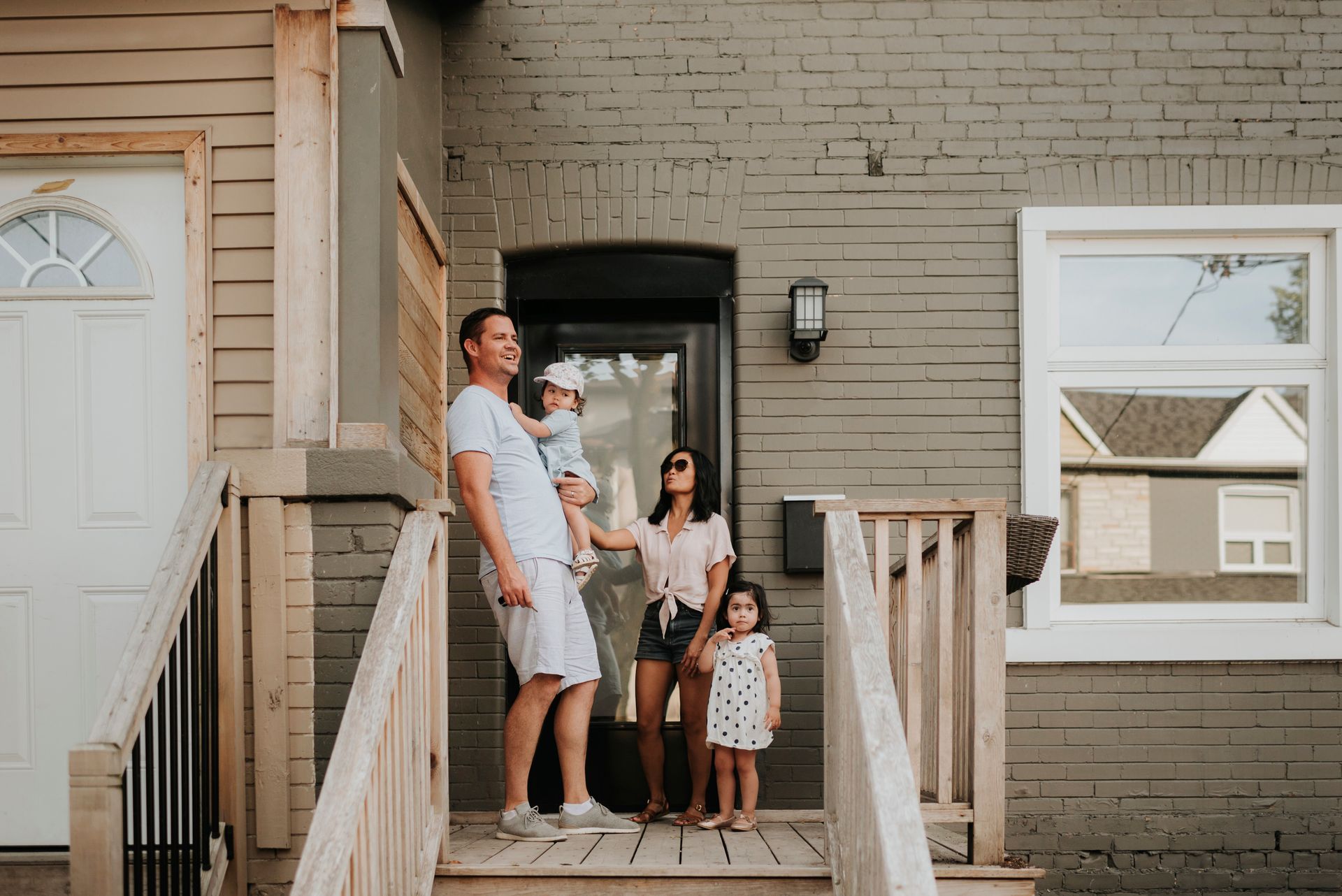 Family of four standing on a front porch, smiling at the camera.