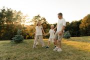 Three people walking together in a grassy field at sunset