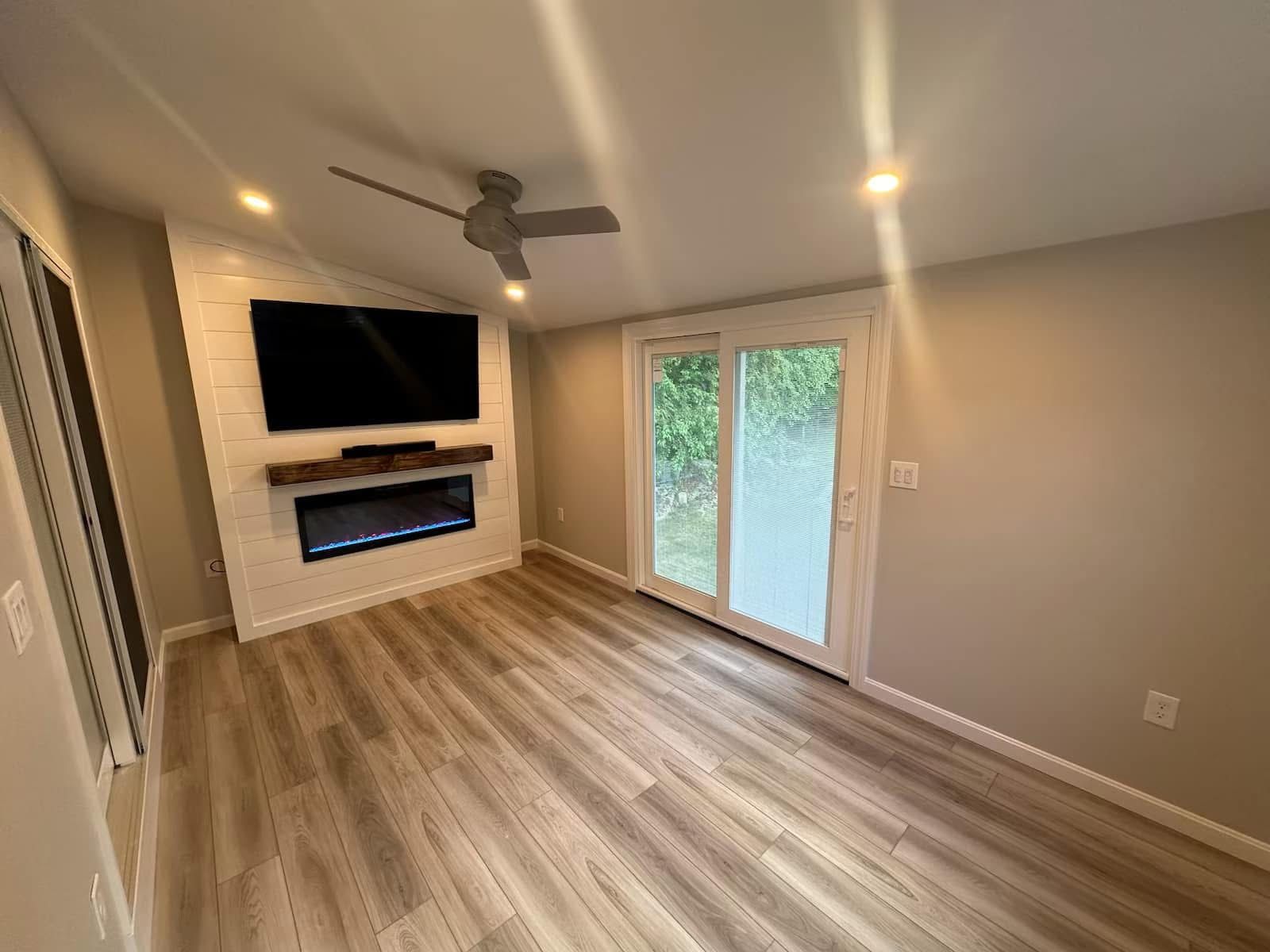 A modern room featuring light wood-look floors, a white brick wall with a mounted TV, and a built-in fireplace.