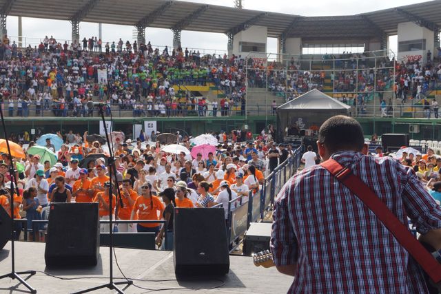 Un guitarrista en el escenario de un estadio se enfrenta a una multitud numerosa 