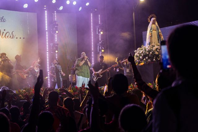 Una banda actúa en un escenario brillantemente iluminado ante una gran multitud que la aclama