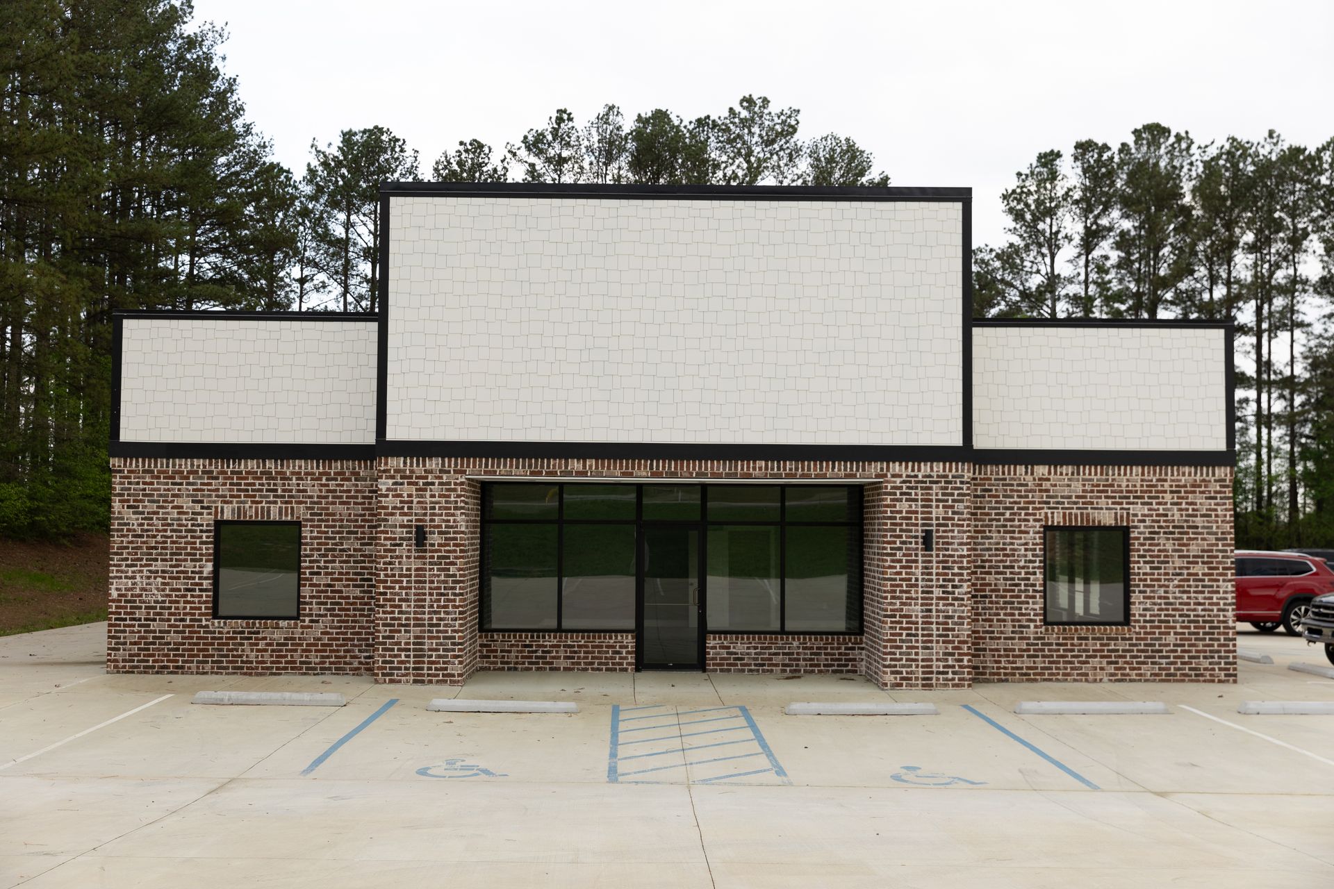 Exterior view of a vacant commercial building with brick facade and large windows.