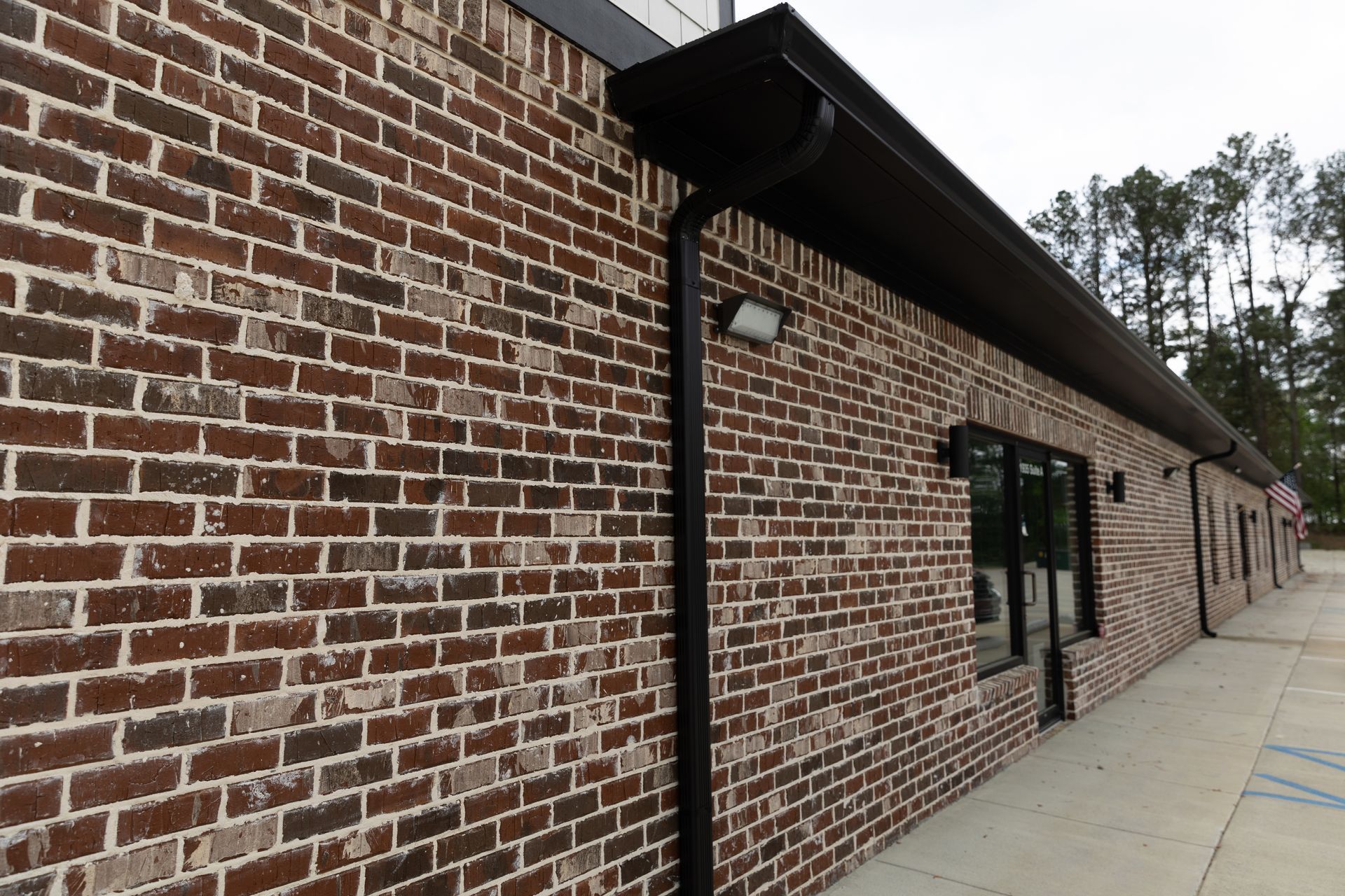 Brick building exterior with dark gutters and windows.