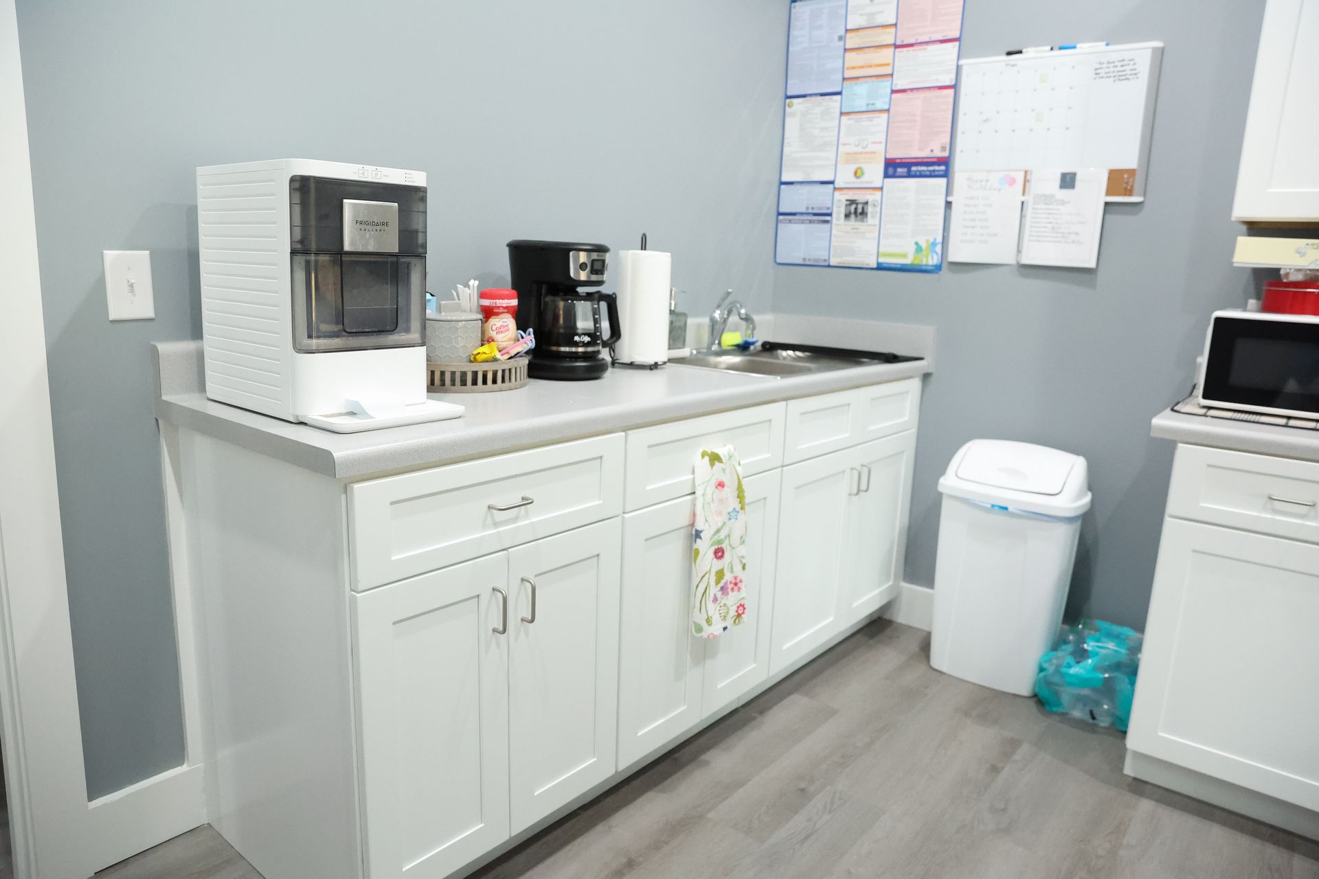 White kitchen cabinets, countertop, appliances, and sink. Blue walls, gray floor.