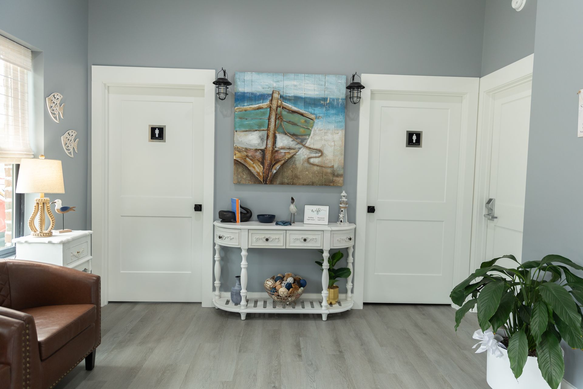 Waiting area with white doors, a boat painting, and a brown leather chair.