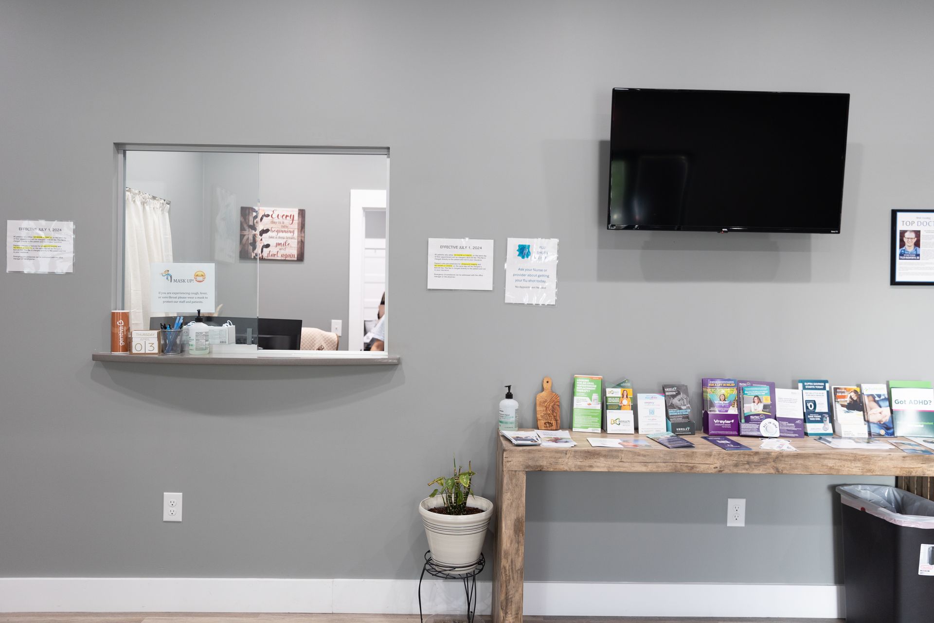 Gray reception area with a desk, TV, and information display.