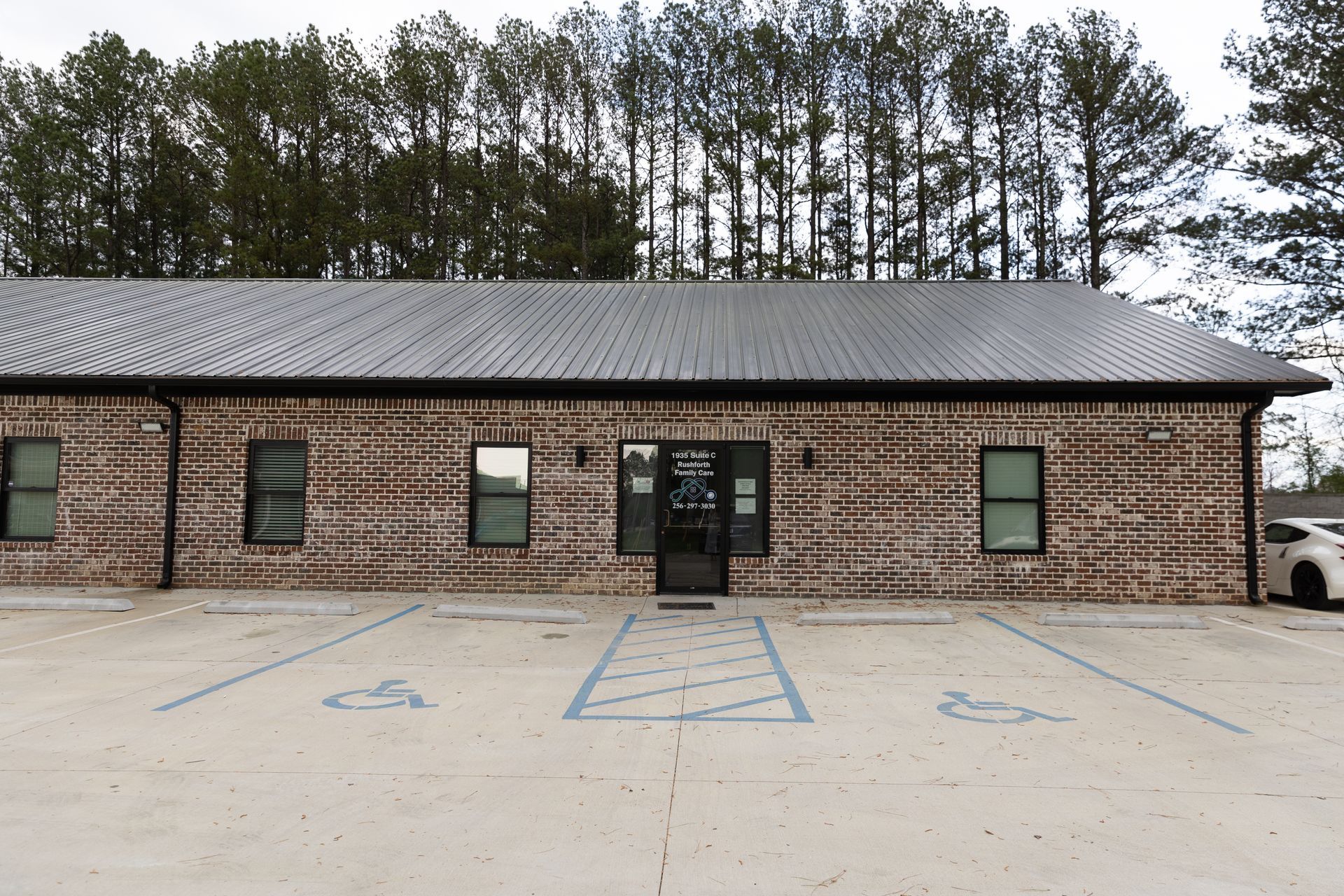 Brick building with metal roof; parking spots, including accessible spots, in front.