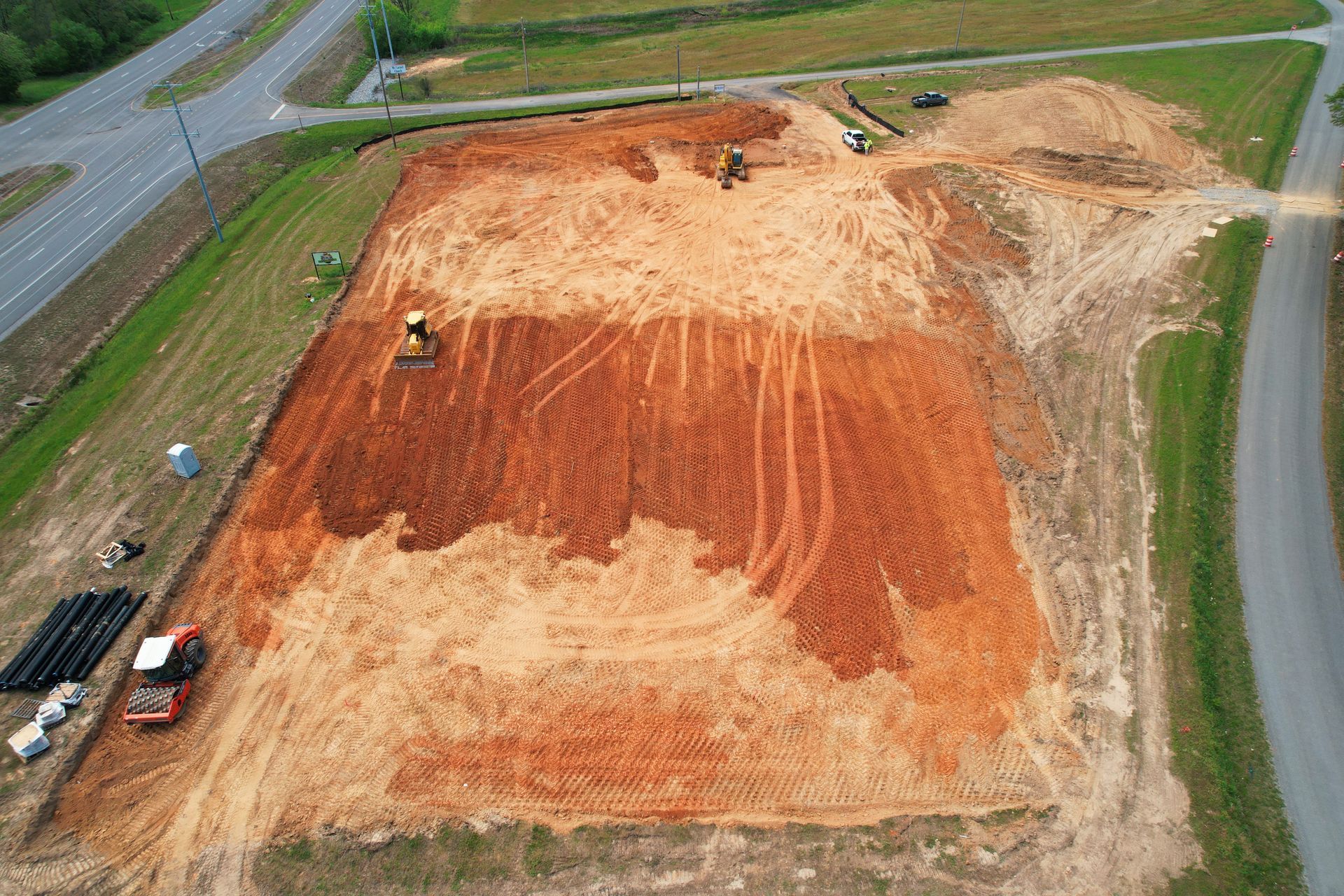 Aerial view of construction site with heavy machinery, moving red soil.