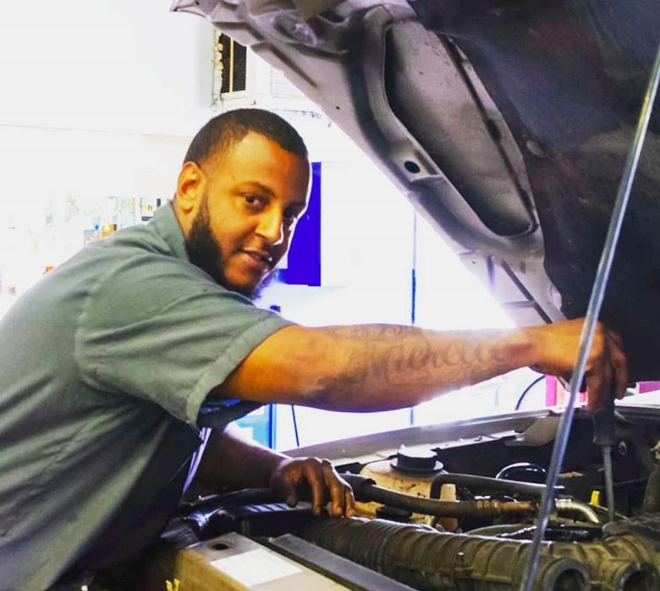 A man is working on a car with the hood open