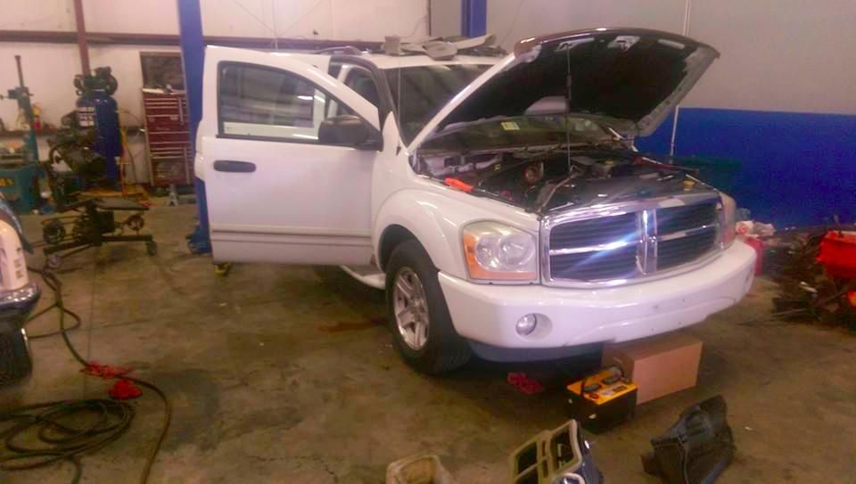 A white dodge ram truck is sitting in a garage with its hood open.