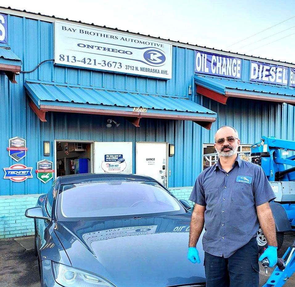 A man is standing in front of a blue building that says oil change diesel