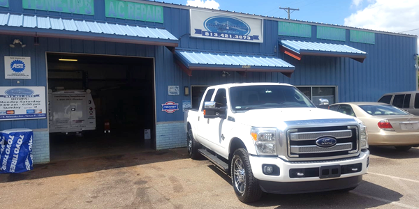A white truck is parked in front of a blue building.